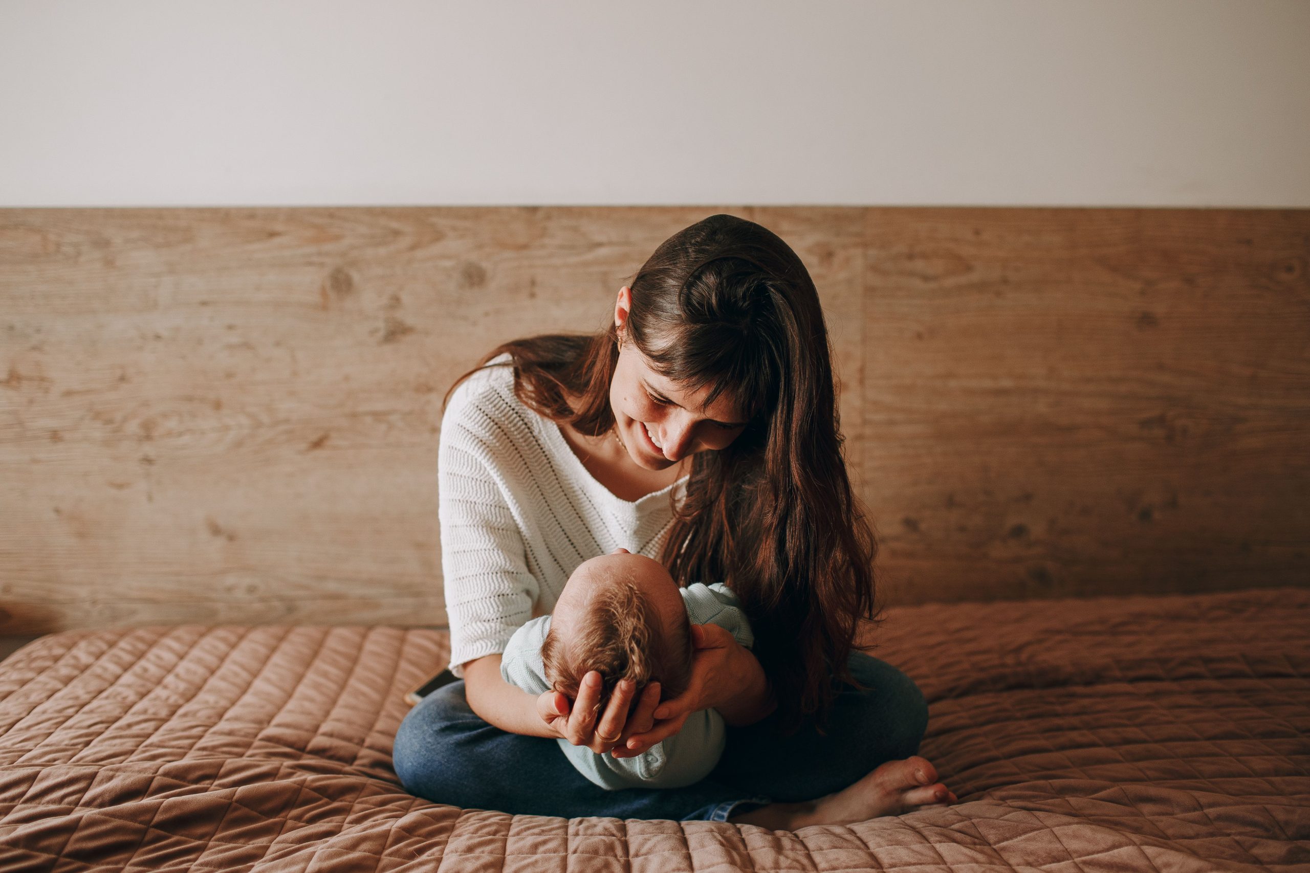 Woman In Edina, MN Smiling At Her Newborn At Home